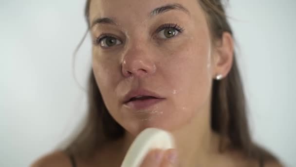Flickan tar bort masken från ansiktet med en svamp. Kosmetologiskt förfarande. — Stockvideo