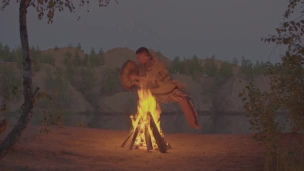 A shaman with a drum jumps in around the fire in clothes for the ceremony. — Stock Video