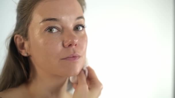 Het meisje verwijdert het masker van haar gezicht met een spons. Cosmetologische procedure. — Stockvideo