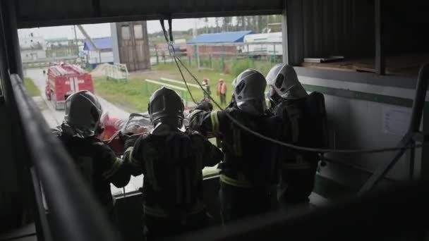 Unterricht für ein Team von Feuerwehrleuten. Rettung einer bewusstlosen Person aus einem verrauchten Raum — Stockvideo