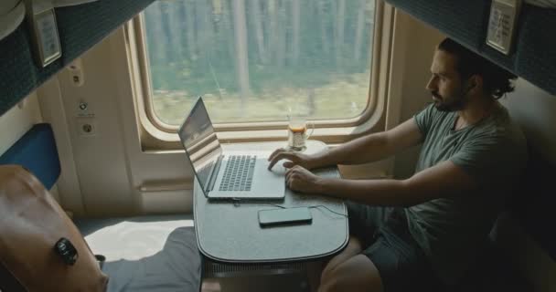 Jovem homem branco trabalhando em um laptop em um compartimento de trem. — Vídeo de Stock