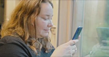 Uzun saçlı tombul bir genç kız, mutlu bir şekilde trenin camından dışarı bakar..