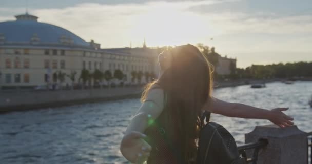Una giovane bella ragazza in prendisole cammina lungo il argine del fiume sulla città vecchia — Video Stock