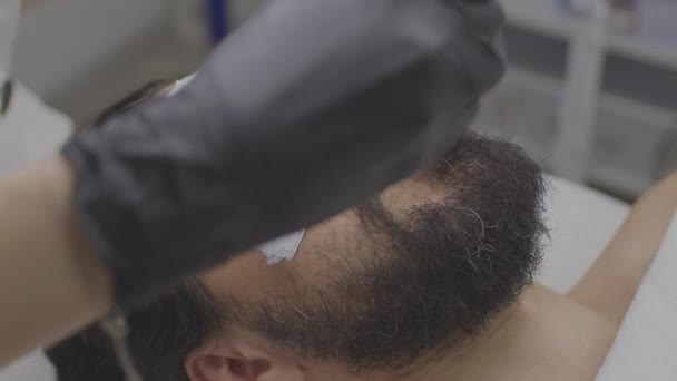 Close-up de um jovem rosto de homem com uma máscara branca de limpeza em seu rosto. — Vídeo de Stock