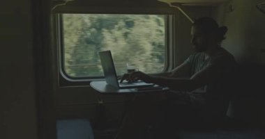 Genç beyaz erkek, tren kompartımanında dizüstü bilgisayarda çalışıyor..