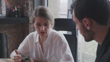 Bir kadın ve bir erkek toplantı odasında bir projeyi tartışıyorlar..