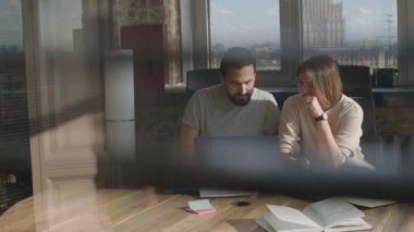 Arkadaşlar ortak bir projede birlikte çalışıyorlar, gülümsüyorlar ve gülüyorlar..