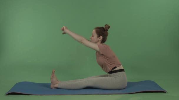 Una chica joven y bonita hace yoga en un fondo de cromakey verde. — Vídeos de Stock