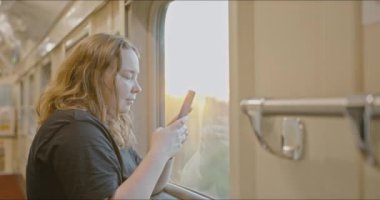 Genç tombul bir kız mutlu bir şekilde tren penceresinden dışarı bakar. Demiryolu yolculuğu.