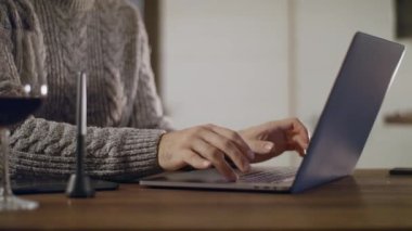 Dizüstü bilgisayarda klavyeye yazı yazan elleri yakın plan çektikten sonra telefonu açar..