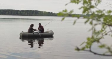 Göldeki şişme bir teknede genç balıkçılar balık tutuyor. Sinematik çekim.