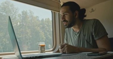 Genç beyaz erkek, tren kompartımanında dizüstü bilgisayarda çalışıyor..