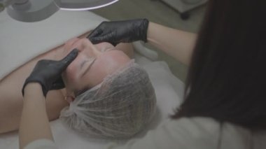 Güzellik salonunda bir kadın yüzüne nemlendirici bir doku maskesi takar..