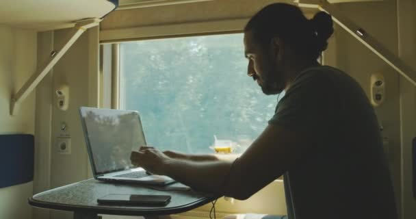 Junger weißer Mann arbeitet in einem Zugabteil an einem Laptop. — Stockvideo