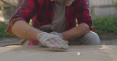 Solunum cihazlı, gözlüklü, parke tahtasını zımpara makinesiyle cilalayan bir adam..