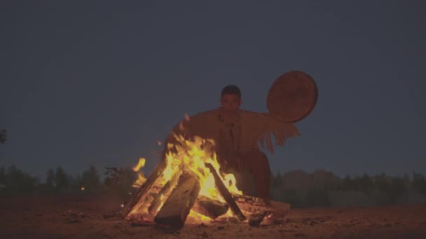 Een sjamaan met een trommel springt in kleding rond het vuur voor de ceremonie. — Stockvideo