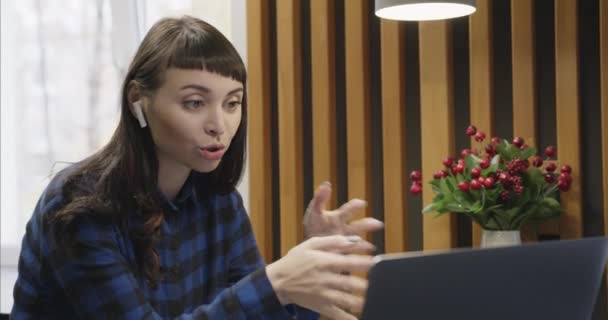 Портрет молодої дівчини в навушниках, що розмовляють перед екраном ноутбука . — стокове відео