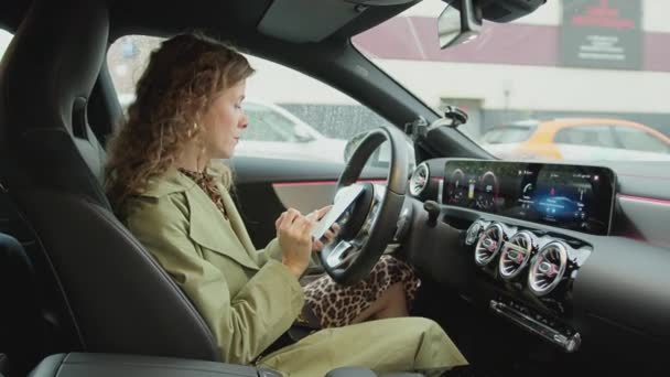 Jovem bela mulher moderna sentada ao volante de um carro premium — Vídeo de Stock