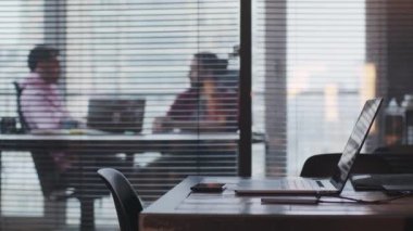 Dizüstü bilgisayarı olan genç bir işadamı bir meslektaşıyla ofiste konuşuyor.