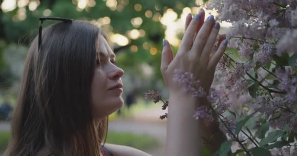 해질 녘 라일락 꽃 사이에 있는 아름다운 카프카스 소녀의 모습. — 비디오