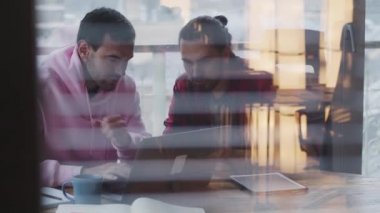 Dizüstü bilgisayarı olan genç bir işadamı bir meslektaşıyla ofiste konuşuyor.