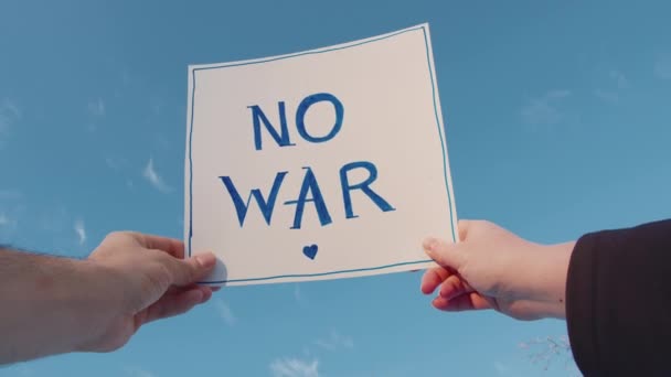 Крупним планом картонний знак з написом без війни на блакитному небі — стокове відео