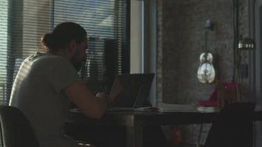 Genç bir çalışan çalışma gününden sonra ofiste oyalanıyor. Fazla mesai.