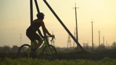 Çakıl taşı bisikleti süren bir bisikletçinin silüeti ormanda yol alıyor.