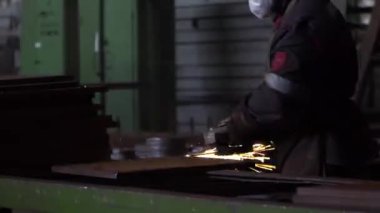 Heavy Industry Engineering Factory Interior with Industrial Worker Using Angle Grinder and Cutting a Metal Tube. Kyiv, Ukraine. 30.03.2022.
