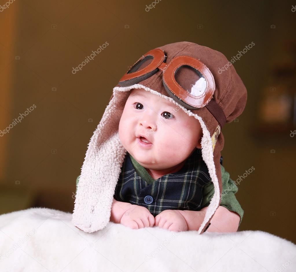 Happy cute 3-month old Asian baby boy playing on bed with colorf
