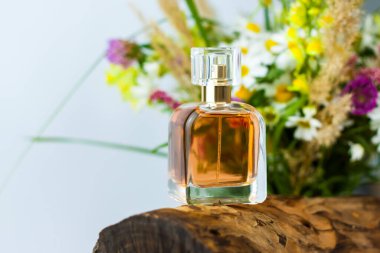 Arka planda bir parfüm şişesi kuru bir kütük, ağaç kabuğu ve bir buket yabani çiçek. Şık görünüş, düzen, kişilik. Banner, metin için bir yer. Reklam ve sunum için arkaplan.