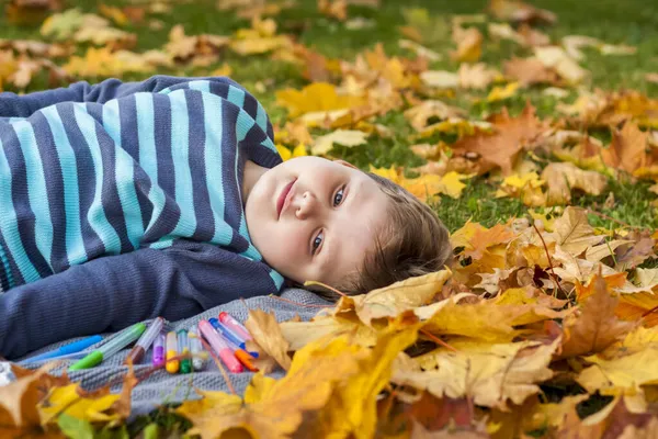 소년은 노트에 무언가를그리고 가을에 나뭇잎에 아이의 시야입니다 다정하고 — 스톡 사진