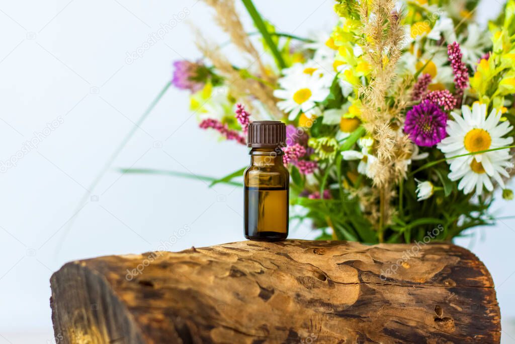 a bottle of cosmetic oil on the background of a dry stump, tree bark and a bouquet of wild flowers. Stylish appearance, layout, personality. Banner, a place for the text. Background for advertising and presentation.