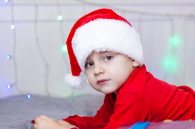 Noel Baba şapkalı şirin bir çocuğun portresi. Gülen komik çocuk. Hediyeler, oyuncaklar, neşe, kutlama. Noel konseri.