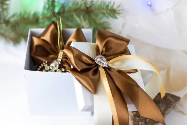 一种圣诞礼物 用漂亮的弓装饰在浅色的背景上 用冷杉枝条装饰 有选择的重点 圣诞节和新年的概念 横幅的背景 — 图库照片