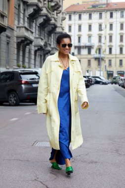 MILAN, İtalya - 25 Eylül 2021: Tamu McPherson soluk sarı, uzun paltolu, elektrik mavisi elbiseli ve yeşil uçlu ayakkabılı Salvatore Ferragamo defilesinden önce, Milan Moda Haftası tarzı