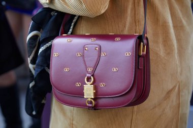 MILAN, İtalya - 24 Şubat 2022: Emporio Armani defilesinden önce altın logolu bordo deri Valentino çantalı kadın, Milan Moda Haftası tarzı