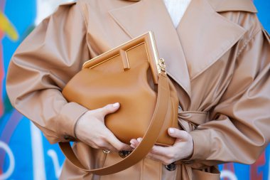 MILAN, İtalya - 23 Şubat 2022 Fendi defilesinden önce kahverengi deri çantalı ve trençkotlu kadın, Milan Moda Haftası tarzı