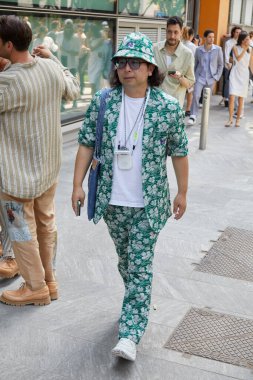 MILAN, İTALYA - 18 Haziran 2022: Emporio Armani moda defilesinden önce, şapka, ceket ve beyaz ve yeşil çiçekli pantolon giyen adam, Milan Moda Haftası tarzı