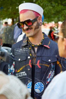 MILAN, ITALY - JUNE 18, 2022: Man with white sailor hat, denim jacket and spaceship designs before Marcelo Burlon County of Milan fashion show, Milan Fashion Week street style