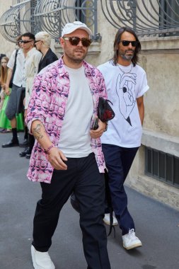 MILAN, ITALY - JUNE 19, 2022: Men with pink shirt with smiling designs and black trousers before Prada fashion show, Milan Fashion Week street style