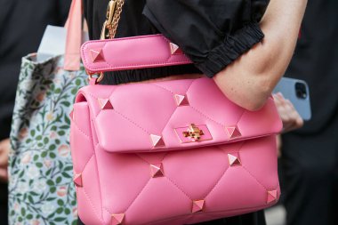 MILAN, ITALY - JUNE 20, 2022: Woman with pink leather bag with golden and pink studs before Giorgio Armani fashion show, Milan Fashion Week street style
