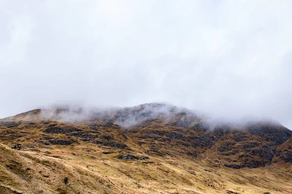 Alçak bulutlar dağlık İskoçya 'nın dağlık arazisinde süzülüyor. Israrlı yağmurun neden olduğu çorak zirveler, dik vadiler ve küçük şelaleler, Argyll Orman Parkı, İskoçya