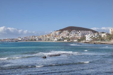 Los Cristianos, Tenerife, Kanarya Adaları, İspanya - 27 Kasım 2020: Arkadaki mavi okyanus ve arkadaki Montana Chayofita tarafından çerçevelenmiş, uzaklardan görülen turistik şehir manzarası