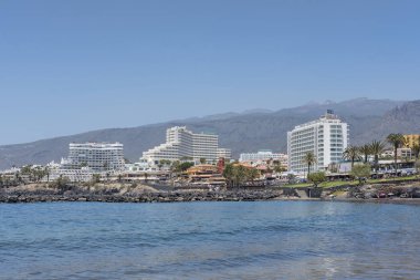 Playa de Troya, Costa Adeje, Tenerife, Canary Islands, Spain - May 1, 2022: calm and tranquil water bay surrounded by fabulous large hotels, in one of the most popular areas in the south of the island