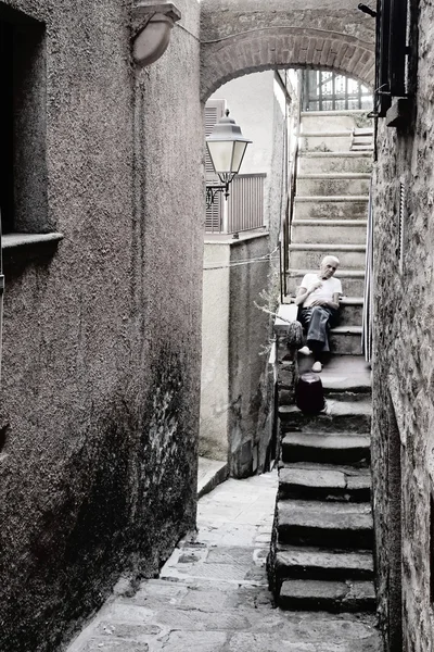 Old man is resting on the stairs of the house in Ancient Village 