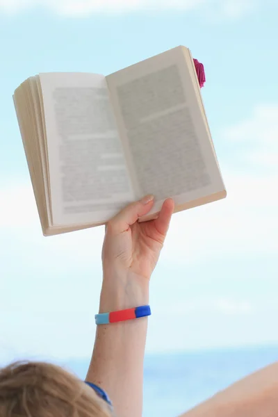 Hand met boek over blauwe hemel — Stockfoto