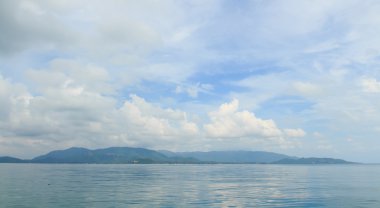 büyük beyaz bulutlar, mavi gökyüzü ve yeşil ocea ile panoramik deniz manzarası