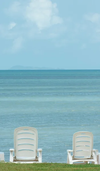 Vista al mar con sombrilla azul y sillas blancas — Foto de Stock