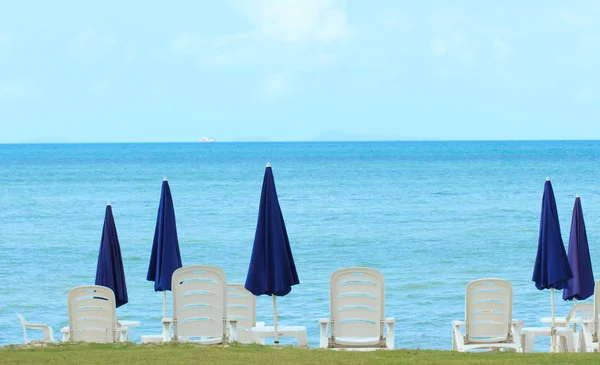 Vista mar com guarda-chuva azul e cadeiras brancas — Fotografia de Stock